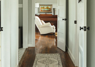 white walled hallway leading to a white recliner chair and wood floors